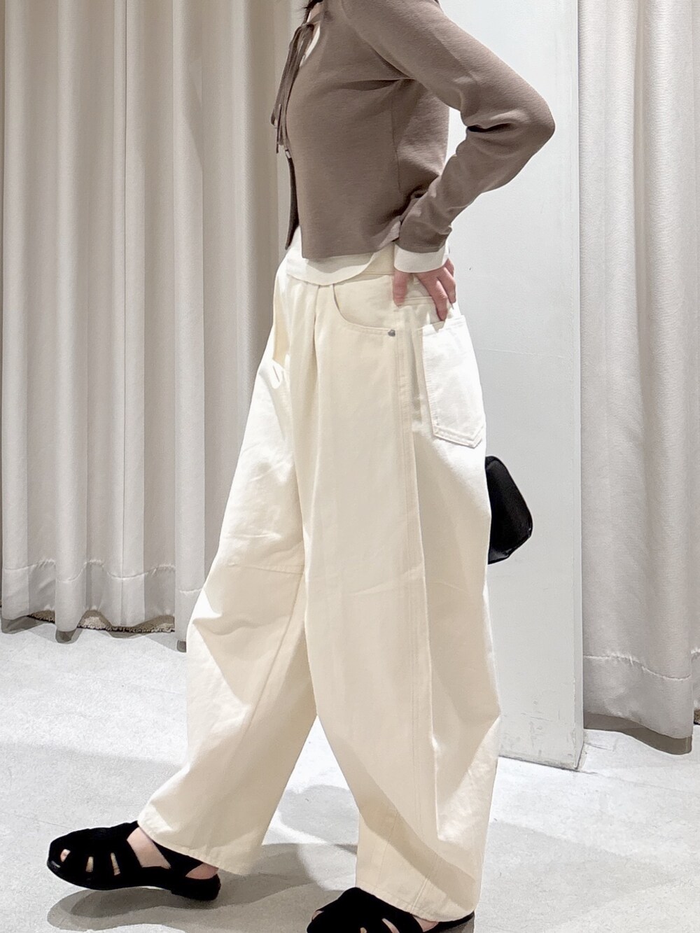 ブラウン系のニット/セーター、ホワイト系のその他パンツ、ブラック系のサンダルを着用したレディースの春コーディネートの5枚目の写真