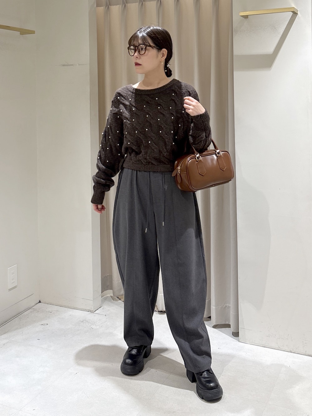 ブラウン系のニット/セーター、グレー系のその他パンツ、ブラウン系のハンドバッグを着用したレディースの冬コーディネートの6枚目の写真