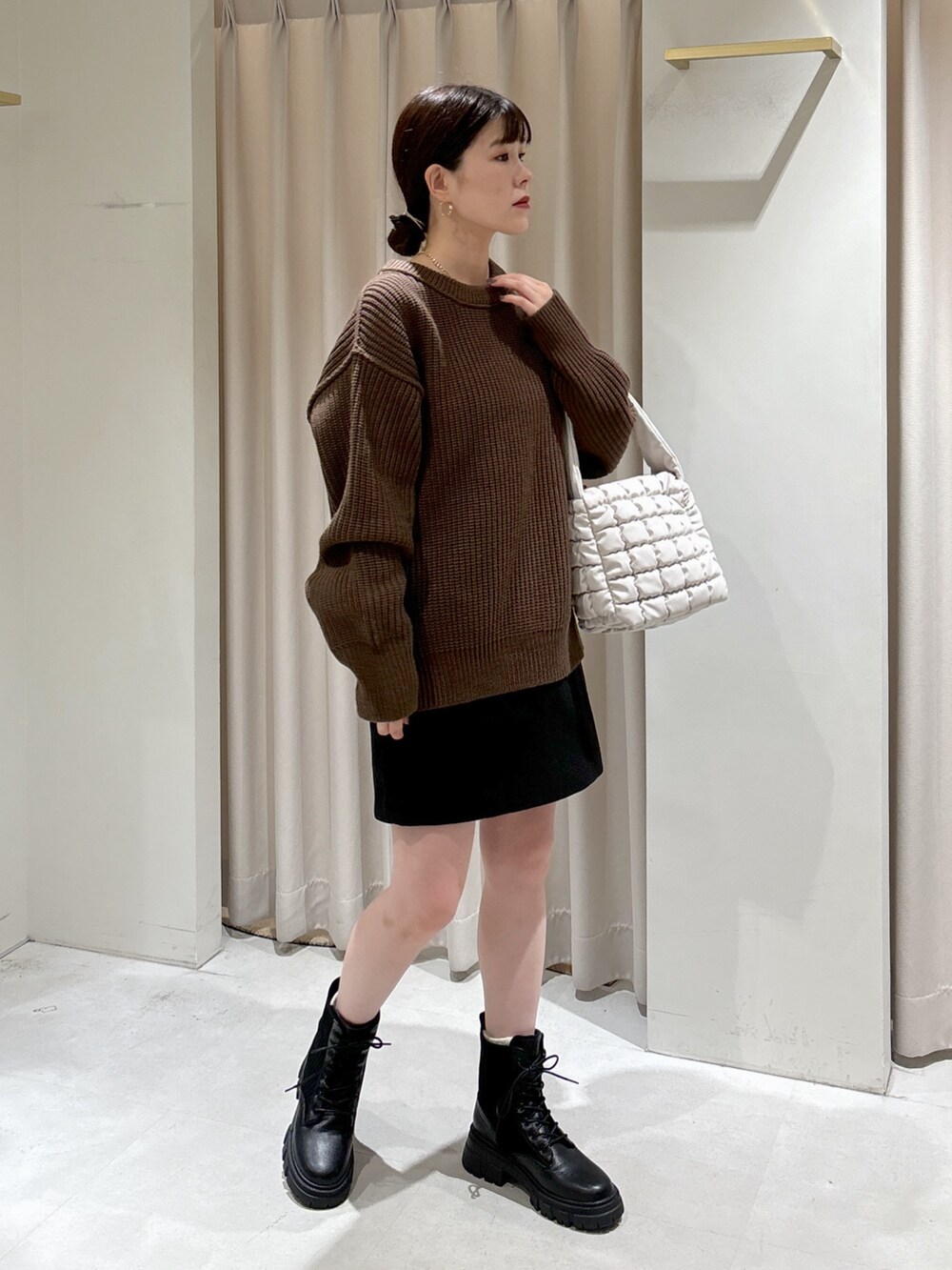 ブラウン系のニット/セーター、ホワイト系のハンドバッグ、ブラック系のスカートを着用したレディースの秋コーディネートの2枚目の写真