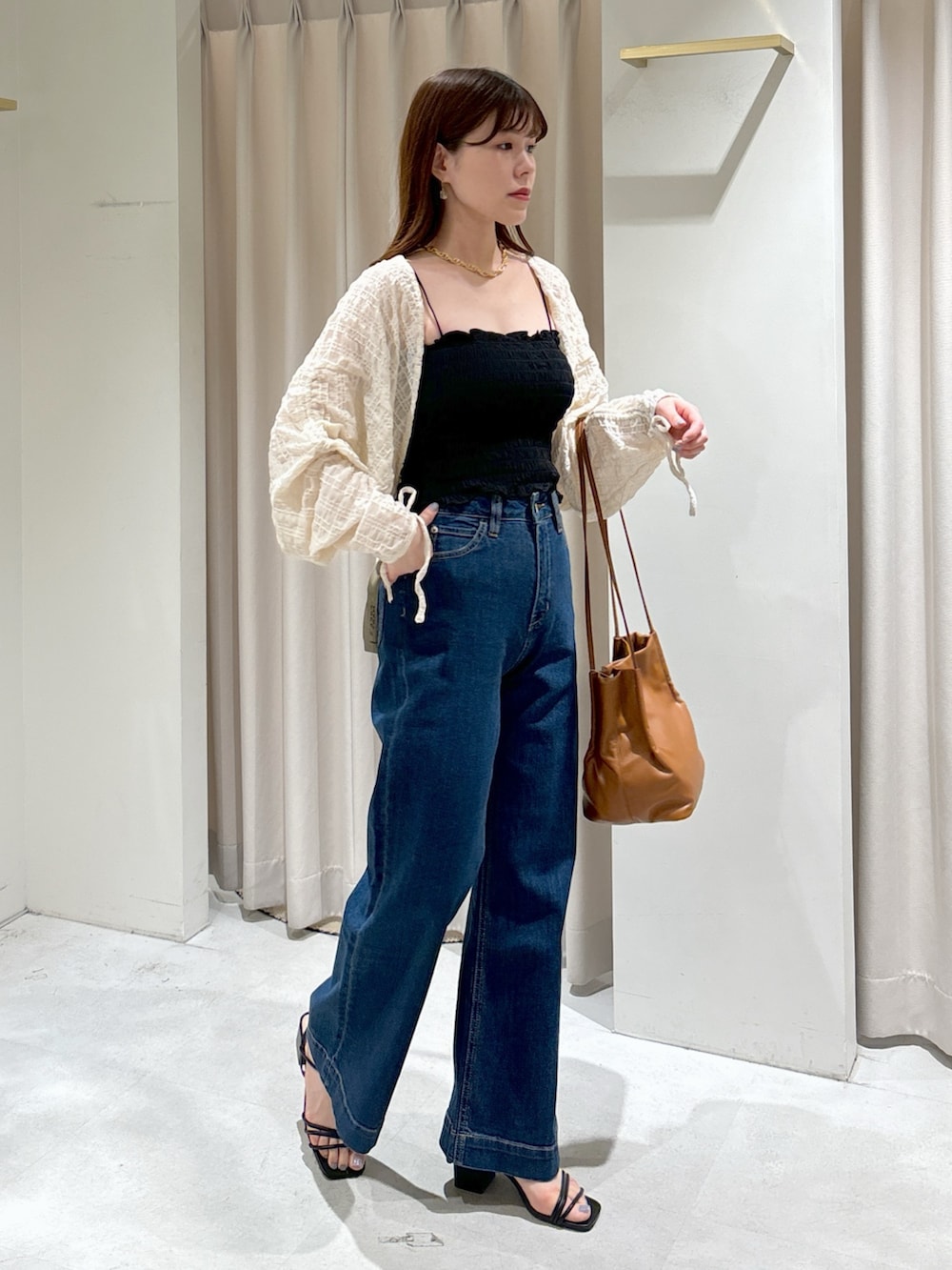 ホワイト系のカーディガン/ボレロ、ブラック系のキャミソール、ブルー系のデニムパンツを着用したレディースの夏コーディネートの2枚目の写真