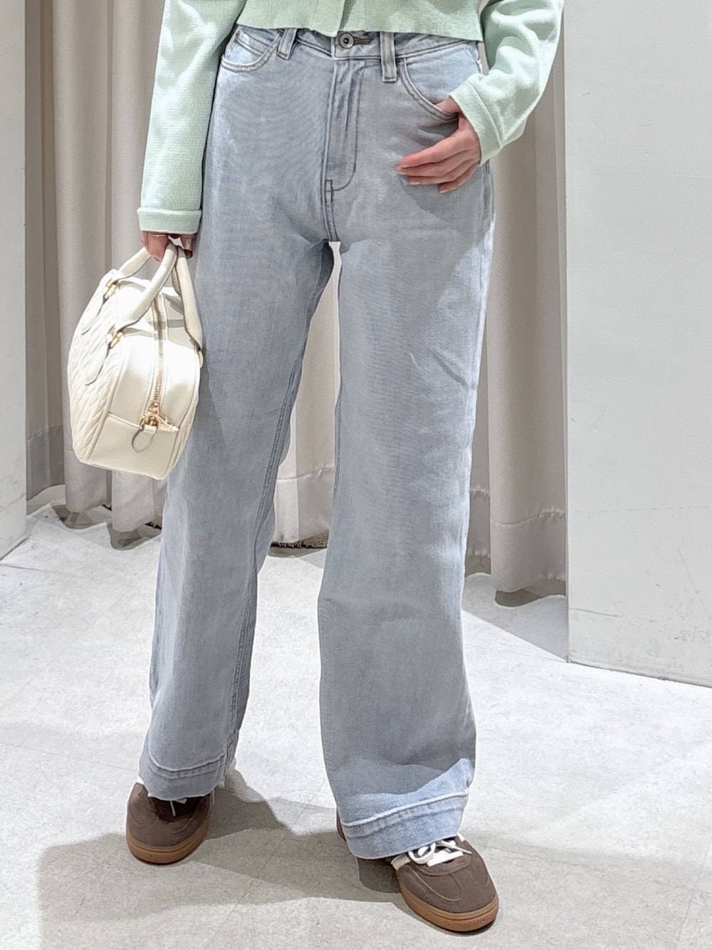 グリーン系のニット/セーター、ホワイト系のボストンバッグ、ブルー系のデニムパンツを着用したレディースの春コーディネートの3枚目の写真