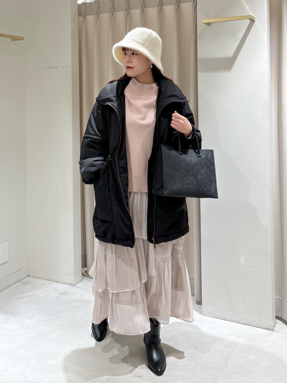 ブラック系のトートバッグ、ホワイト系のスカート、ブラック系のブーツを着用したレディースの冬コーディネートの6枚目の写真