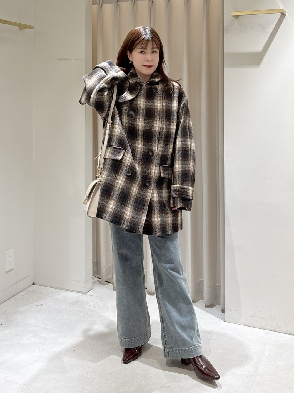 レッド系のニット/セーター、ブラウン系のトートバッグ、ブルー系のデニムパンツを着用したレディースの秋コーディネートの10枚目の写真