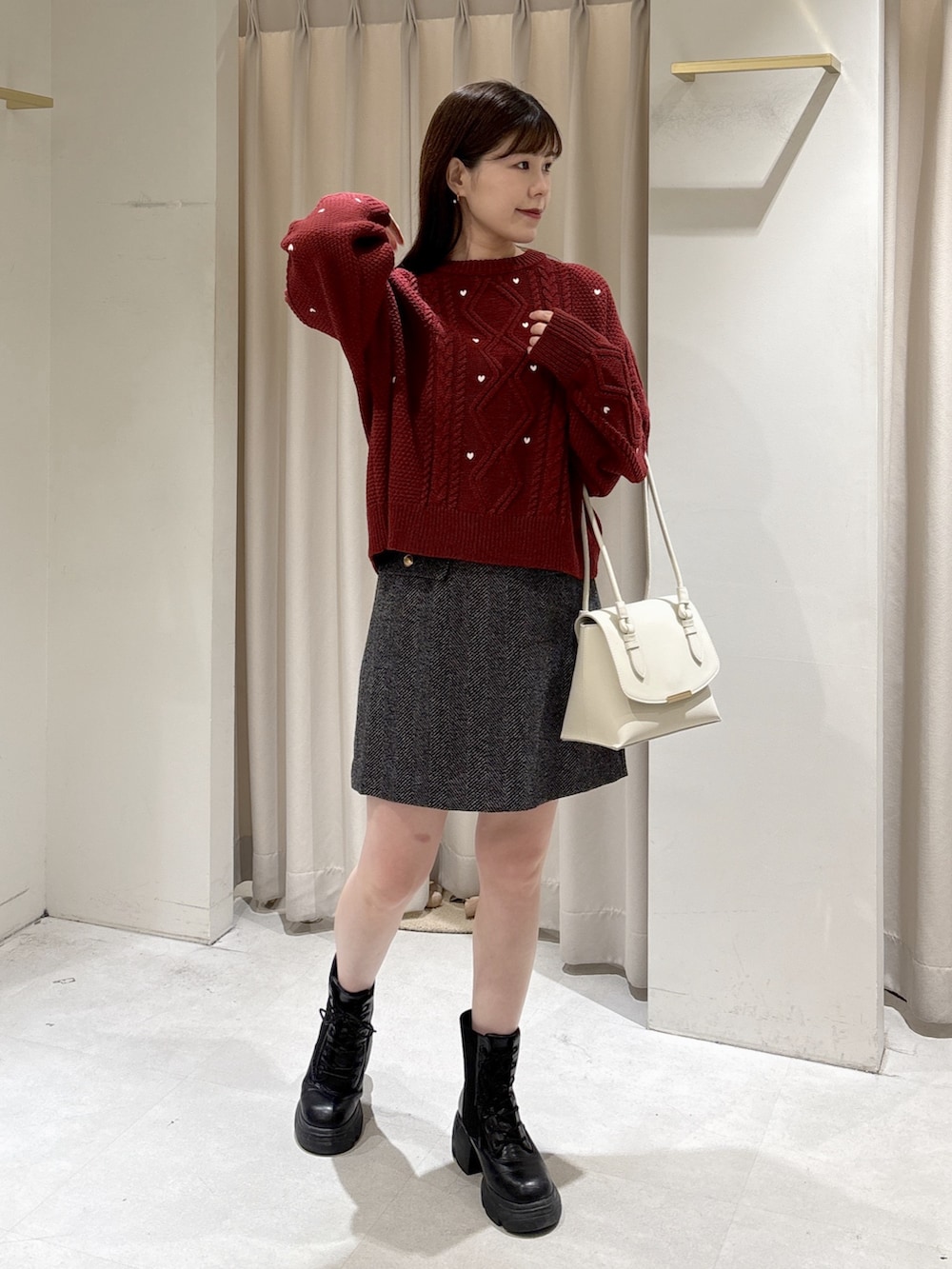レッド系のニット/セーター、ホワイト系のショルダーバッグ、ブラック系のスカートを着用したレディースの冬コーディネートの2枚目の写真
