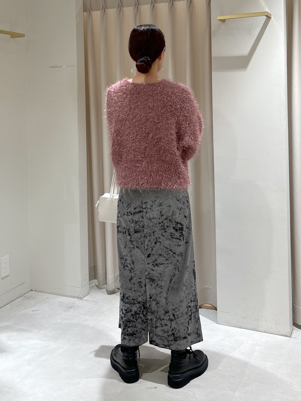 グレー系のステンカラーコート、ホワイト系のショルダーバッグ、ブラック系のブーツを着用したレディースの冬コーディネートの7枚目の写真