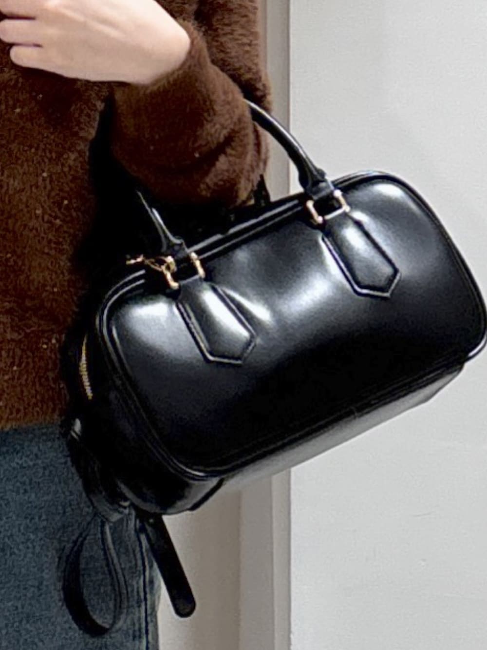 ブラウン系のニット/セーター、ブラック系のハンドバッグ、ブルー系のデニムパンツを着用したレディースの冬コーディネートの5枚目の写真