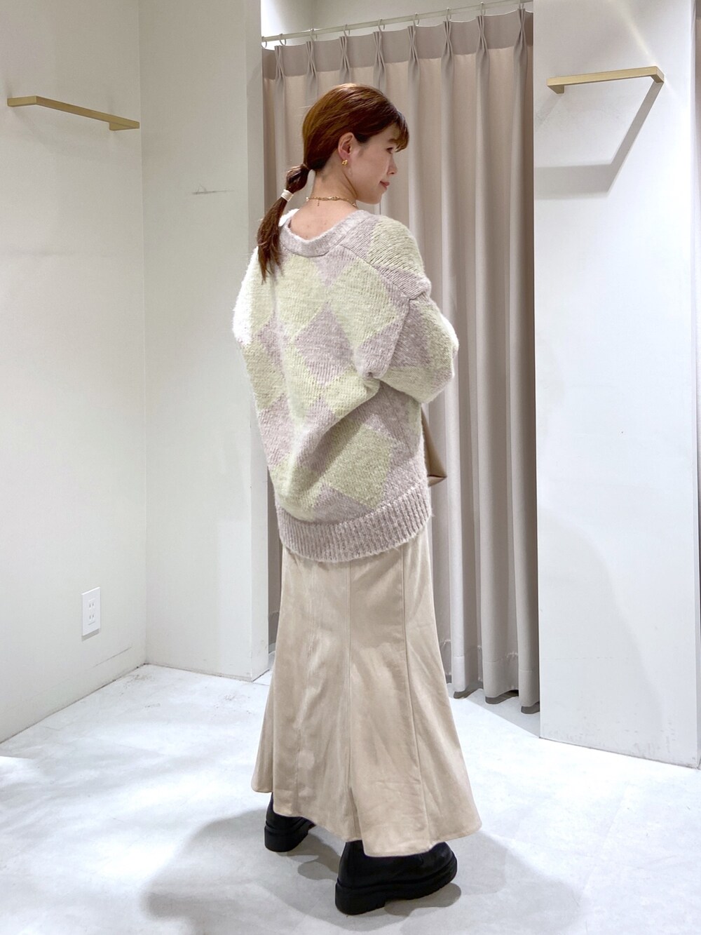 ベージュ系のショルダーバッグ、ブラック系のブーツ、ホワイト系のスカートを着用したレディースの秋コーディネートの4枚目の写真