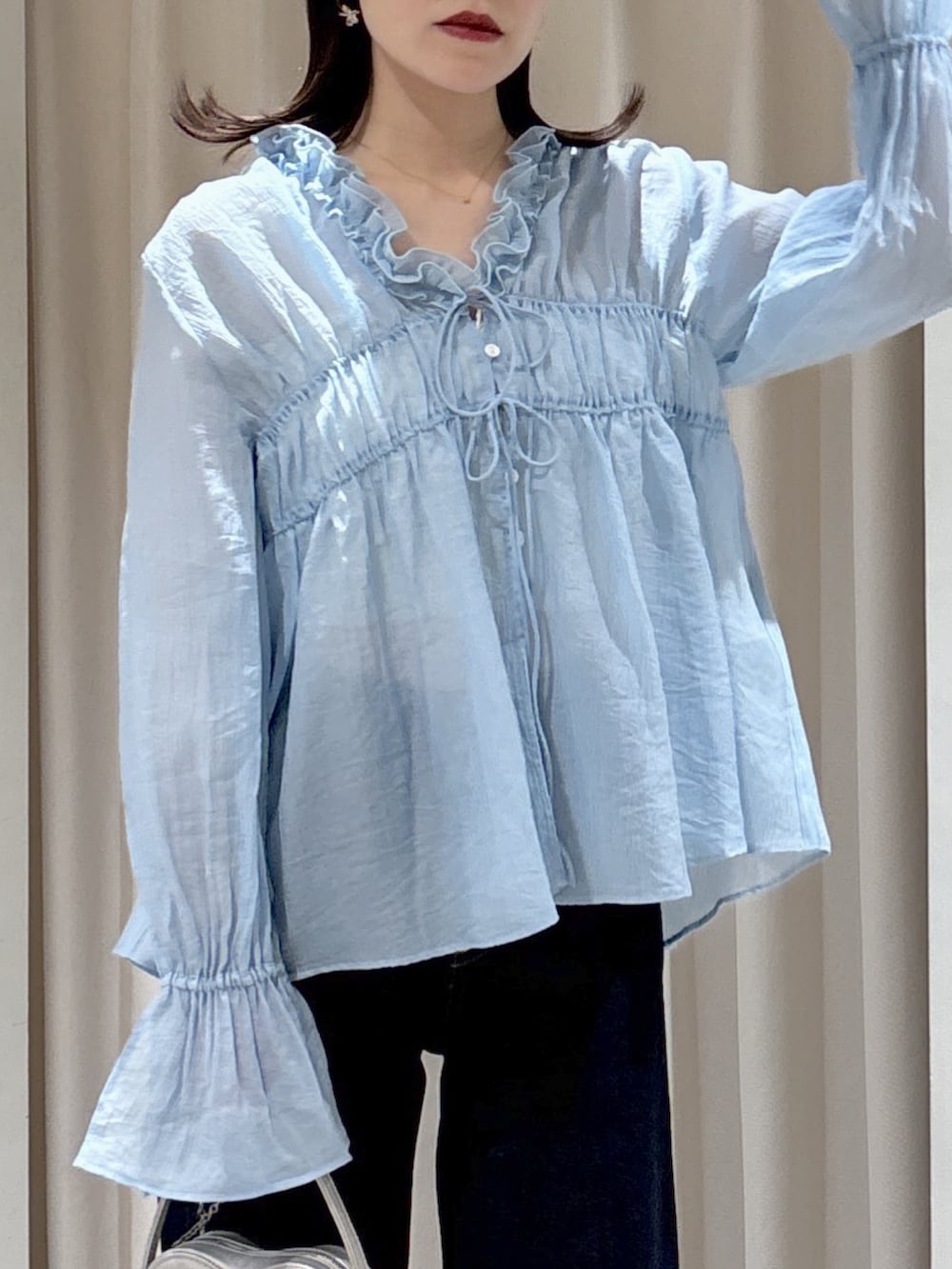 ブラウン系のテーラードジャケット、ホワイト系のハンドバッグ、ブルー系のデニムパンツを着用したレディースの春コーディネートの7枚目の写真