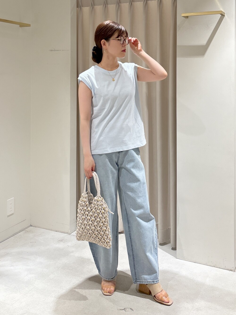 ブルー系のTシャツ/カットソー、ブルー系のデニムパンツ、ホワイト系のハンドバッグを着用したレディースの春コーディネートの2枚目の写真