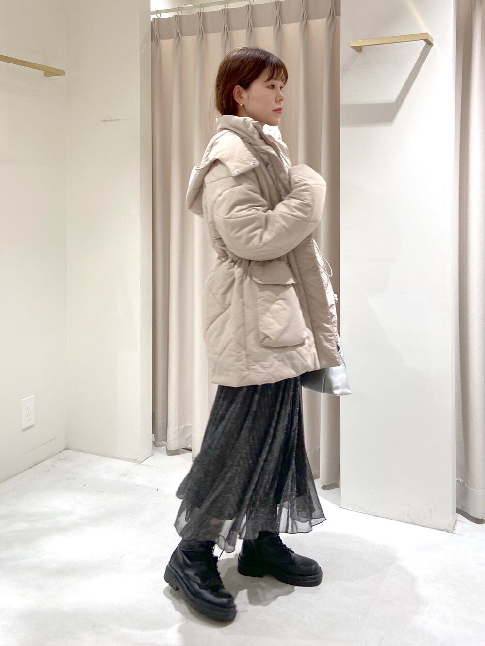 ベージュ系のダウンジャケット/コート、ブラック系のスカート、シルバー系のショルダーバッグを着用したレディースの秋コーディネートの4枚目の写真