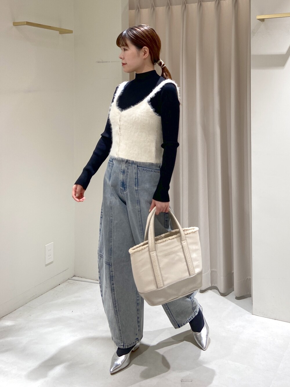 ブラック系のニット/セーター、シルバー系のトートバッグ、ブルー系のデニムパンツを着用したレディースの冬コーディネートの5枚目の写真