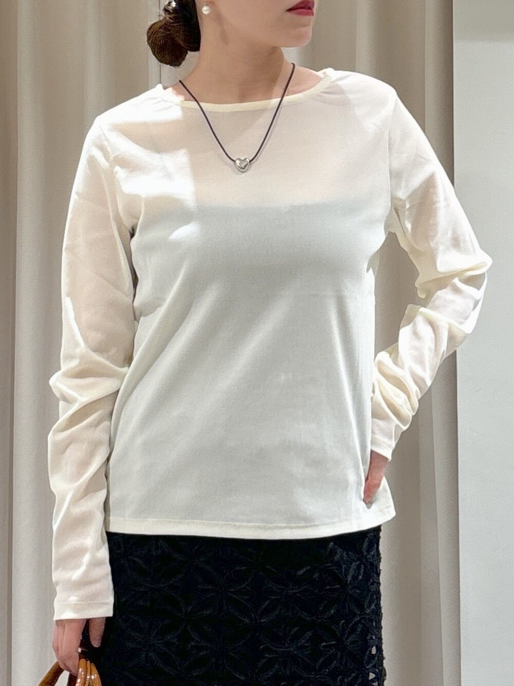 ブラック系のスカート、ベージュ系のショルダーバッグ、ブラック系のブーツを着用したレディースの冬コーディネートの7枚目の写真