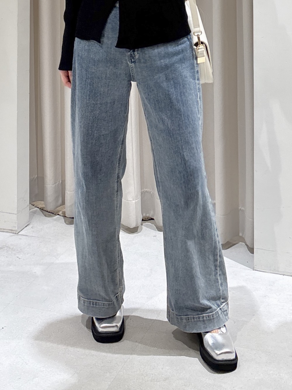 ブラック系のニット/セーター、ホワイト系のハンドバッグ、ブルー系のデニムパンツを着用したレディースの冬コーディネートの5枚目の写真