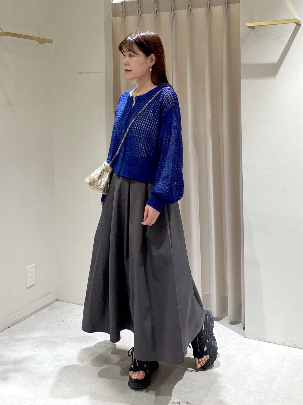 ブルー系のカーディガン/ボレロ、ホワイト系のタンクトップ、グレー系のスカートを着用したレディースの春コーディネートの2枚目の写真