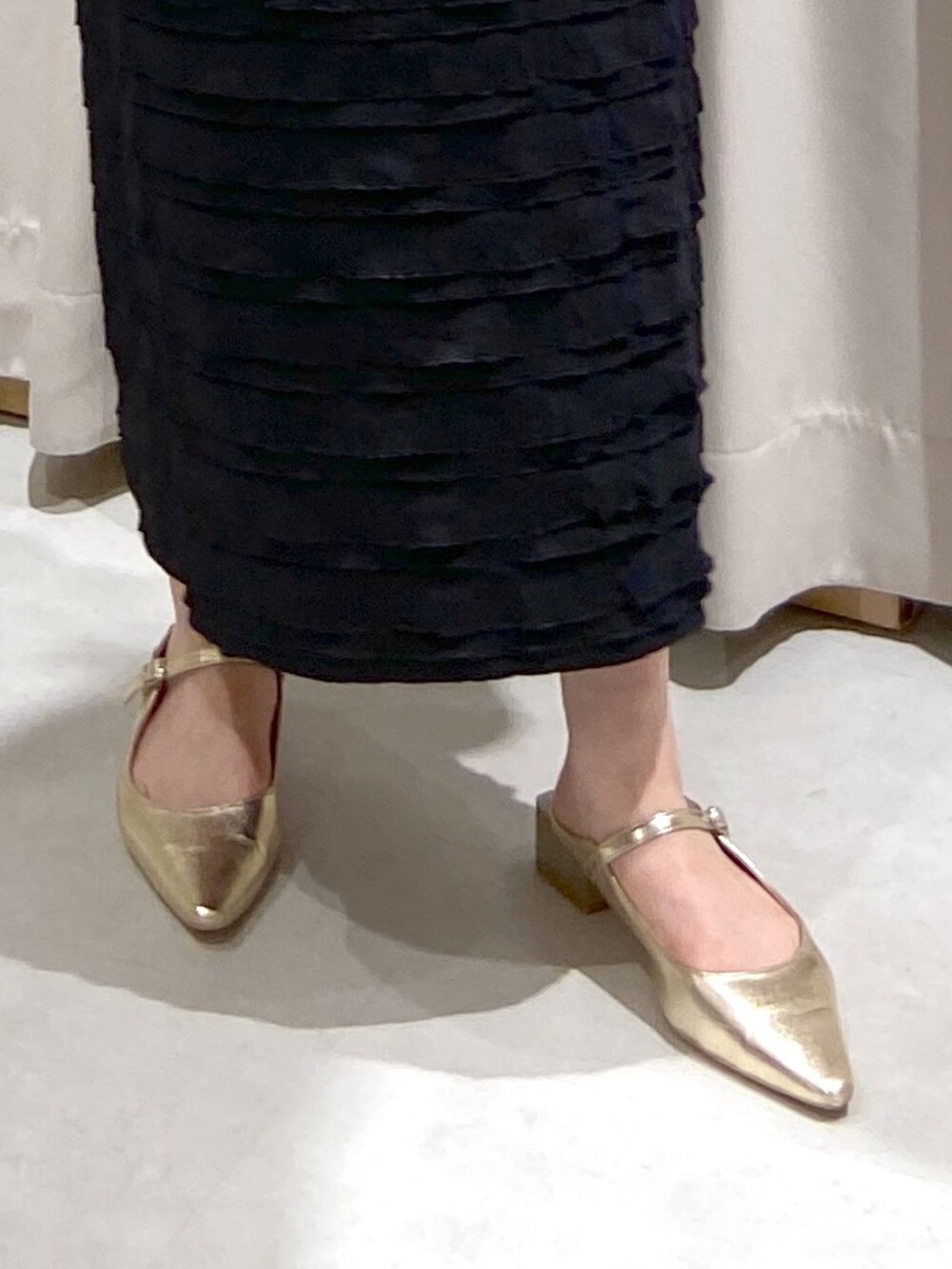 ブラック系のスカート、ブルー系のニット/セーター、ブラウン系のショルダーバッグを着用したレディースの春コーディネートの4枚目の写真