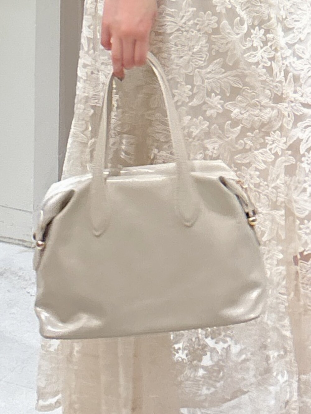 グレー系のニット/セーター、ホワイト系のスカート、ホワイト系のボストンバッグを着用したレディースの夏コーディネートの6枚目の写真