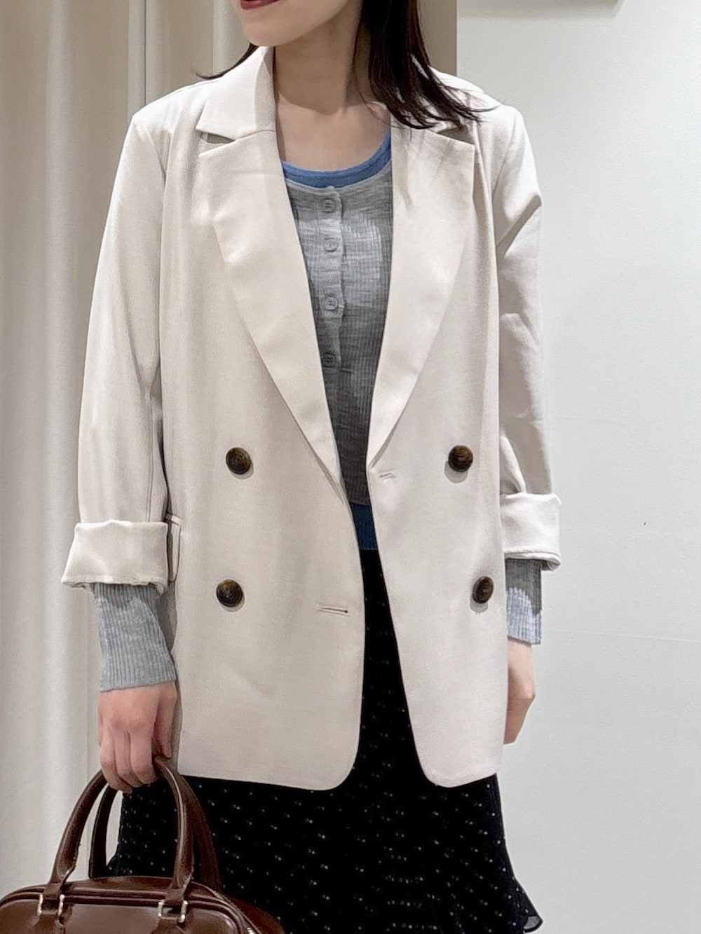 ベージュ系のブルゾン、グレー系のニット/セーター、ブラウン系のハンドバッグを着用したレディースの春コーディネートの3枚目の写真