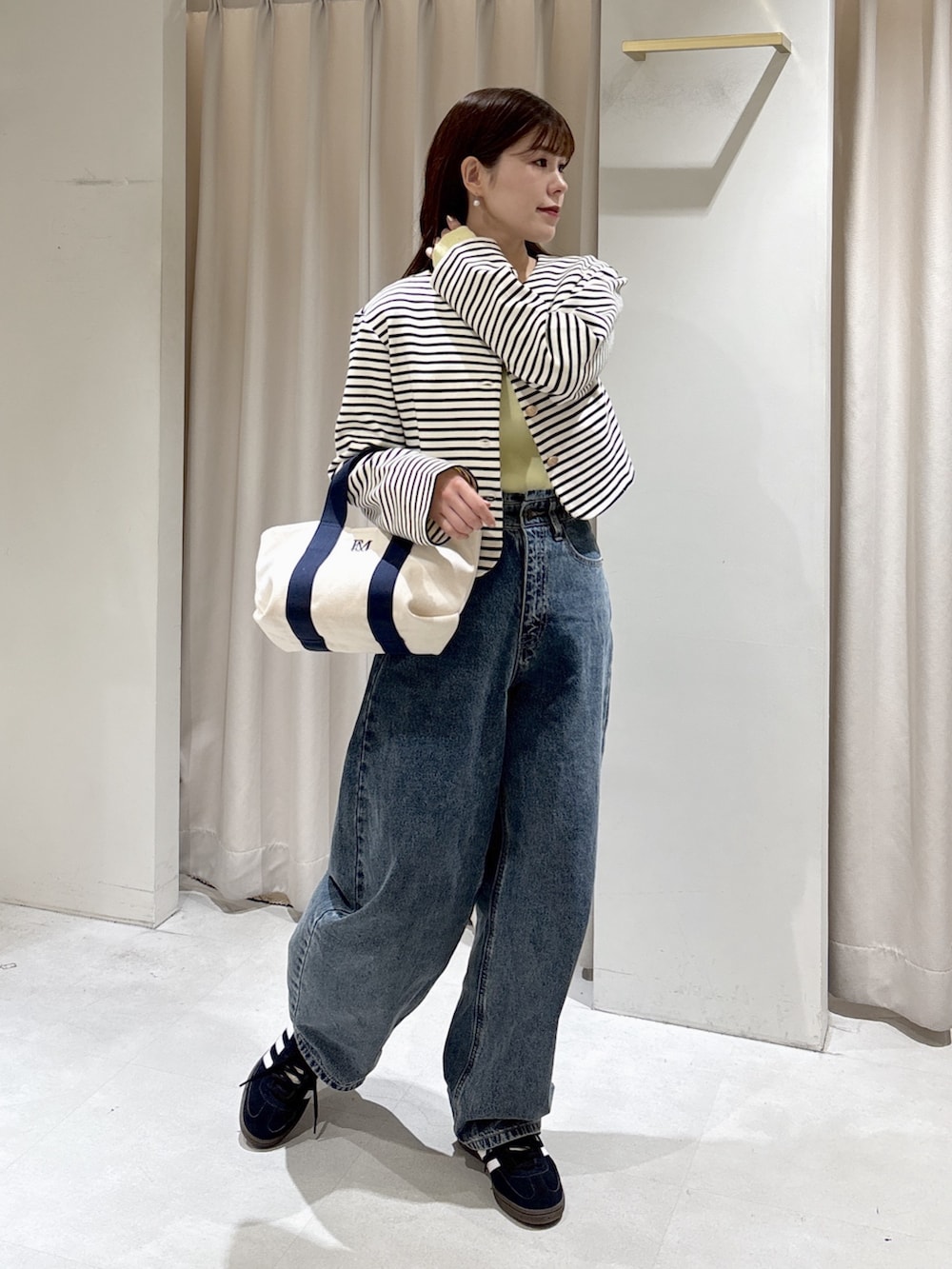 ブラック系のノーカラージャケット、イエロー系のニット/セーター、ブルー系のデニムパンツを着用したレディースの冬コーディネートの7枚目の写真