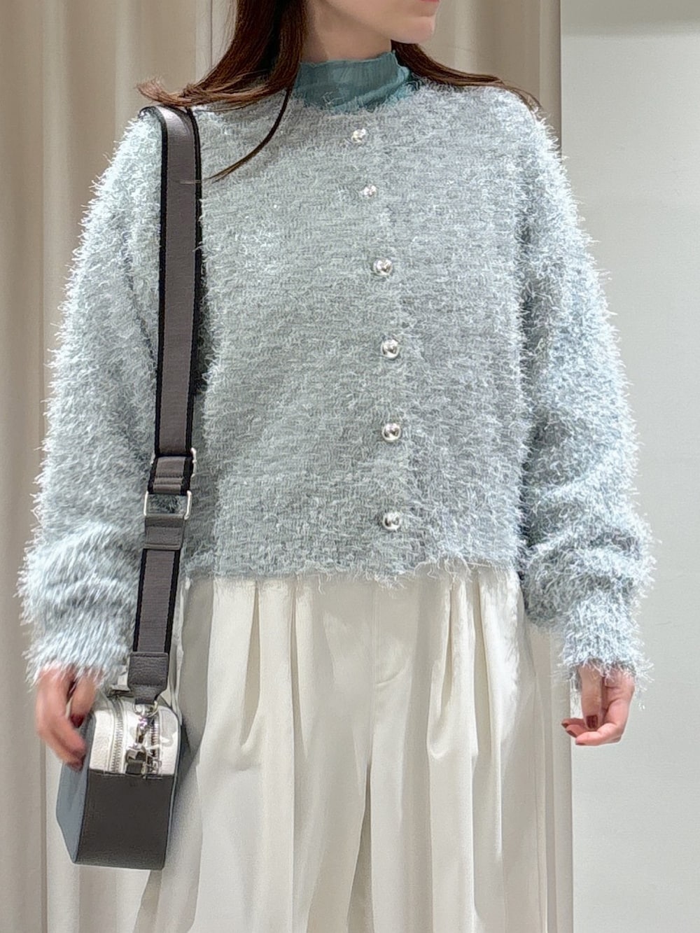 グリーン系のカーディガン/ボレロ、グリーン系のTシャツ/カットソー、ホワイト系のスラックスを着用したレディースの冬コーディネートの5枚目の写真