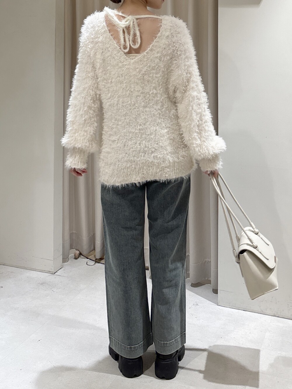 ホワイト系のニット/セーター、ブルー系のデニムパンツ、ホワイト系のショルダーバッグを着用したレディースの冬コーディネートの4枚目の写真