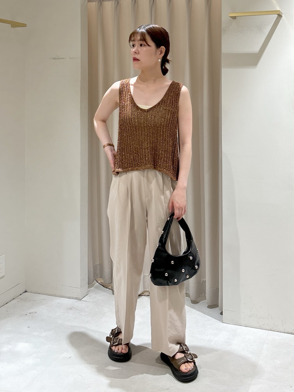 ブラウン系のベスト、ホワイト系のキャミソール、ブラック系のハンドバッグを着用したレディースの夏コーディネートの6枚目の写真