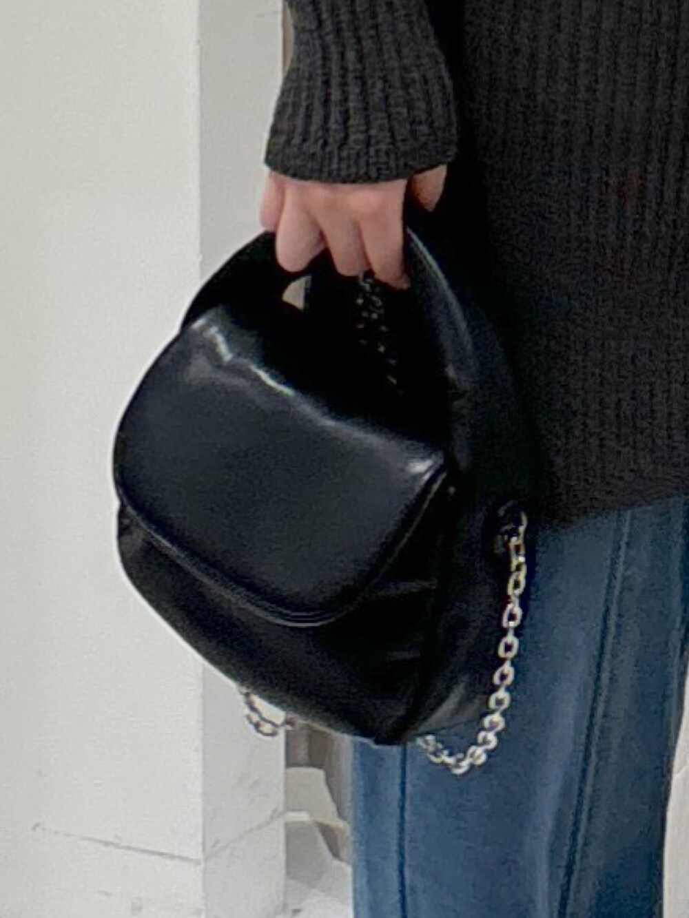 グレー系のワンピース、ブラック系のショルダーバッグ、ブルー系のデニムパンツを着用したレディースの冬コーディネートの6枚目の写真