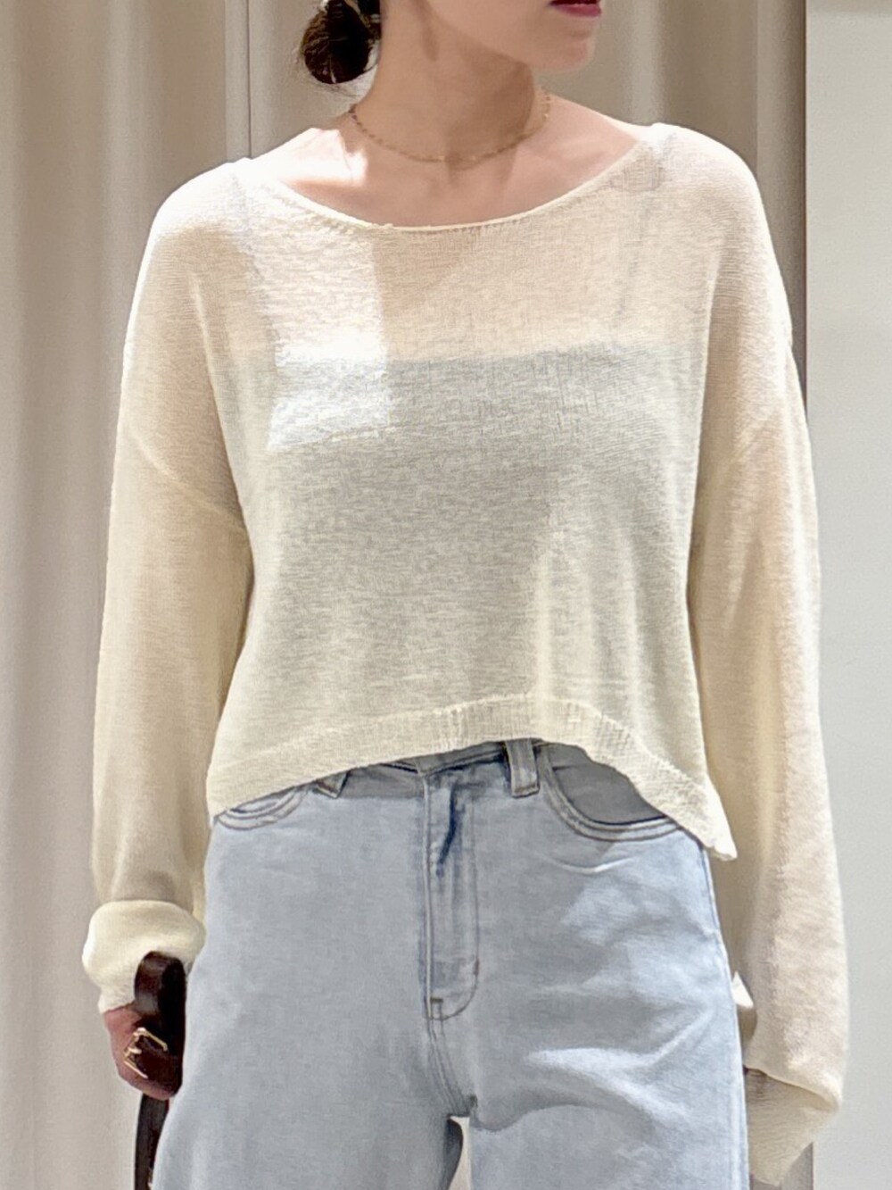 ブラウン系のハンドバッグ、ホワイト系のニット/セーター、ブラック系のキャミソールを着用したレディースの秋コーディネートの2枚目の写真