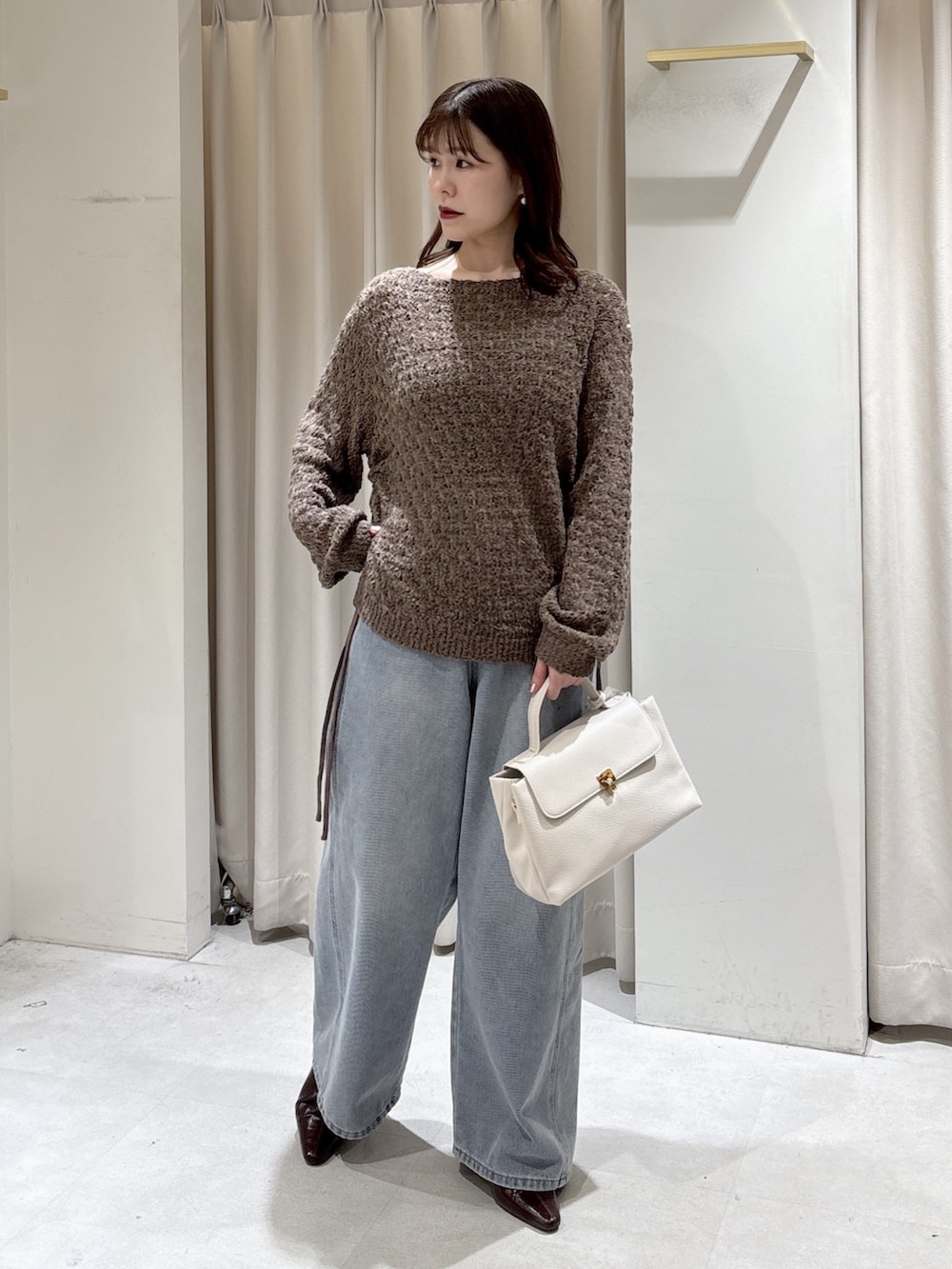 ブラウン系のニット/セーター、ホワイト系のショルダーバッグ、ブルー系のデニムパンツを着用したレディースの冬コーディネートの2枚目の写真