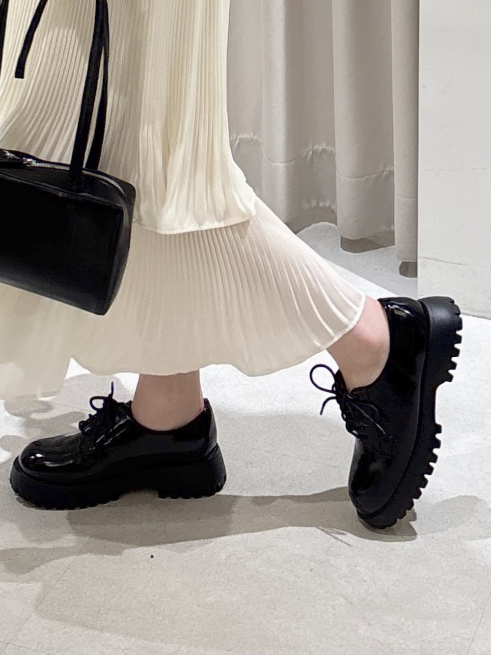 ホワイト系のスウェット、ホワイト系のスカート、ブラック系のショルダーバッグを着用したレディースの春コーディネートの7枚目の写真