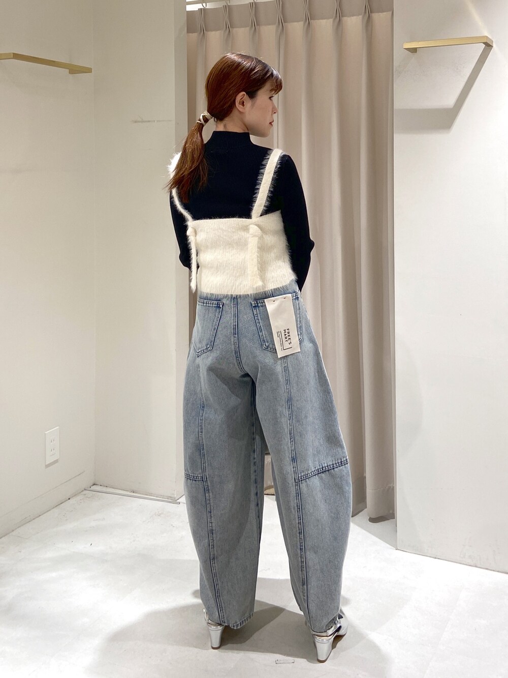 ホワイト系のベスト、ブラック系のニット/セーター、ブルー系のデニムパンツを着用したレディースの冬コーディネートの2枚目の写真