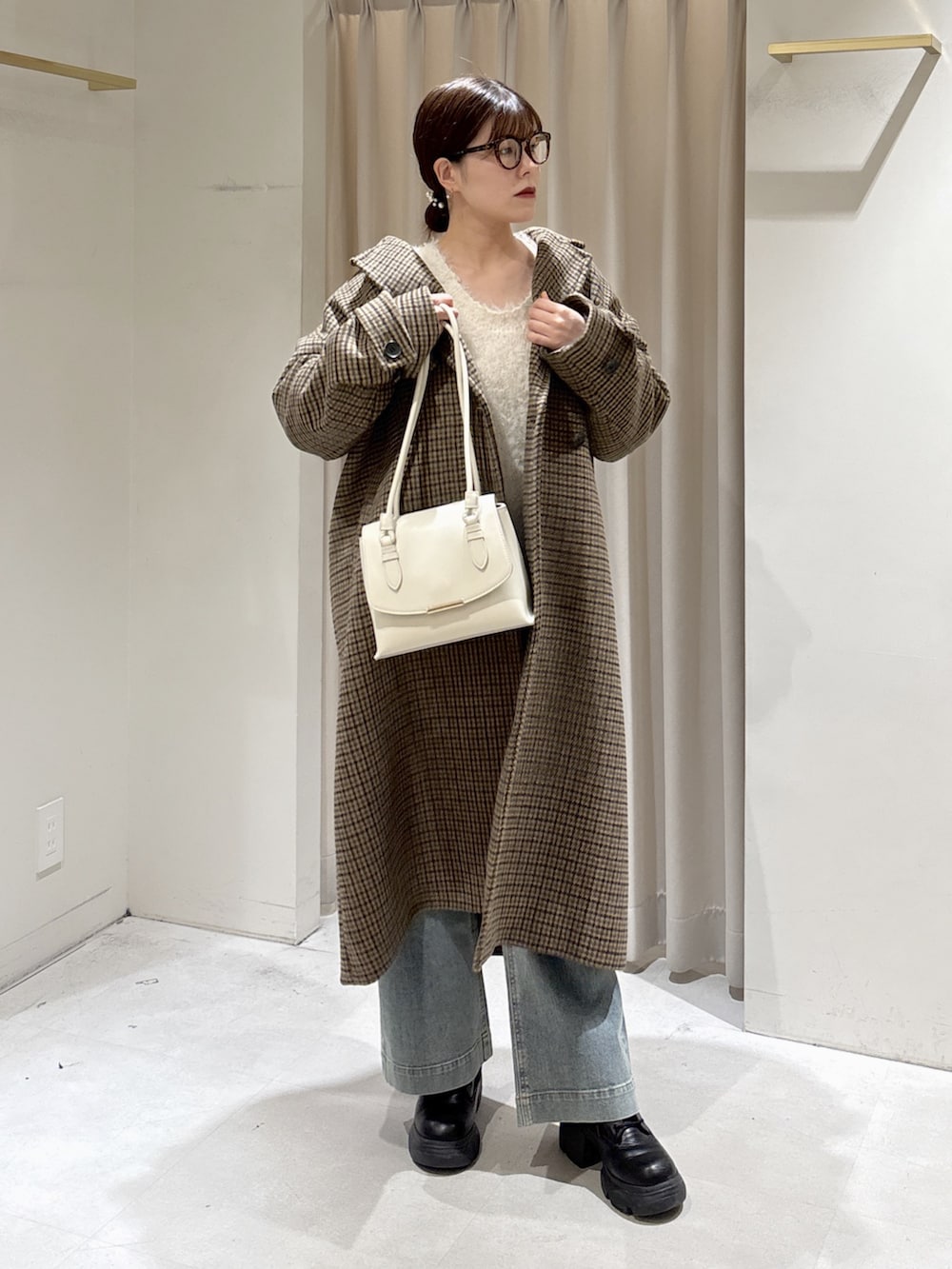 ベージュ系のチェスターコート、ホワイト系のニット/セーター、ホワイト系のショルダーバッグを着用したレディースの冬コーディネートの2枚目の写真