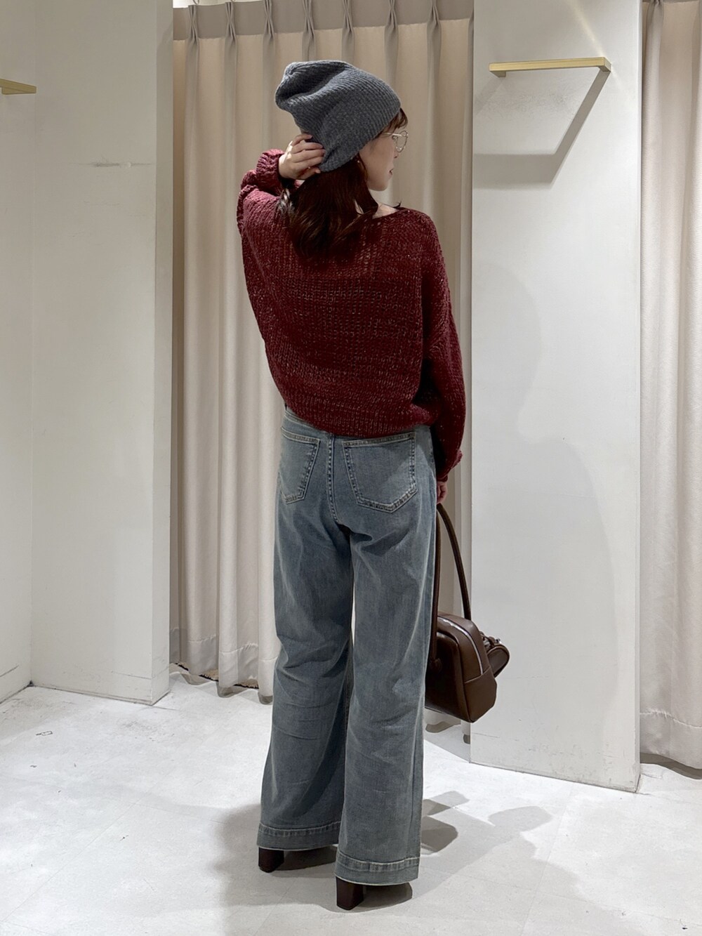 レッド系のニット/セーター、ブラウン系のトートバッグ、ブルー系のデニムパンツを着用したレディースの秋コーディネートの8枚目の写真