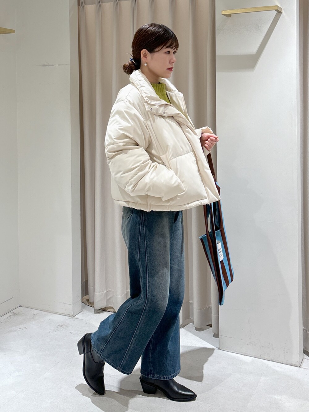 ホワイト系のブルゾン、グリーン系のニット/セーター、ブラウン系のショルダーバッグを着用したレディースの冬コーディネートの2枚目の写真