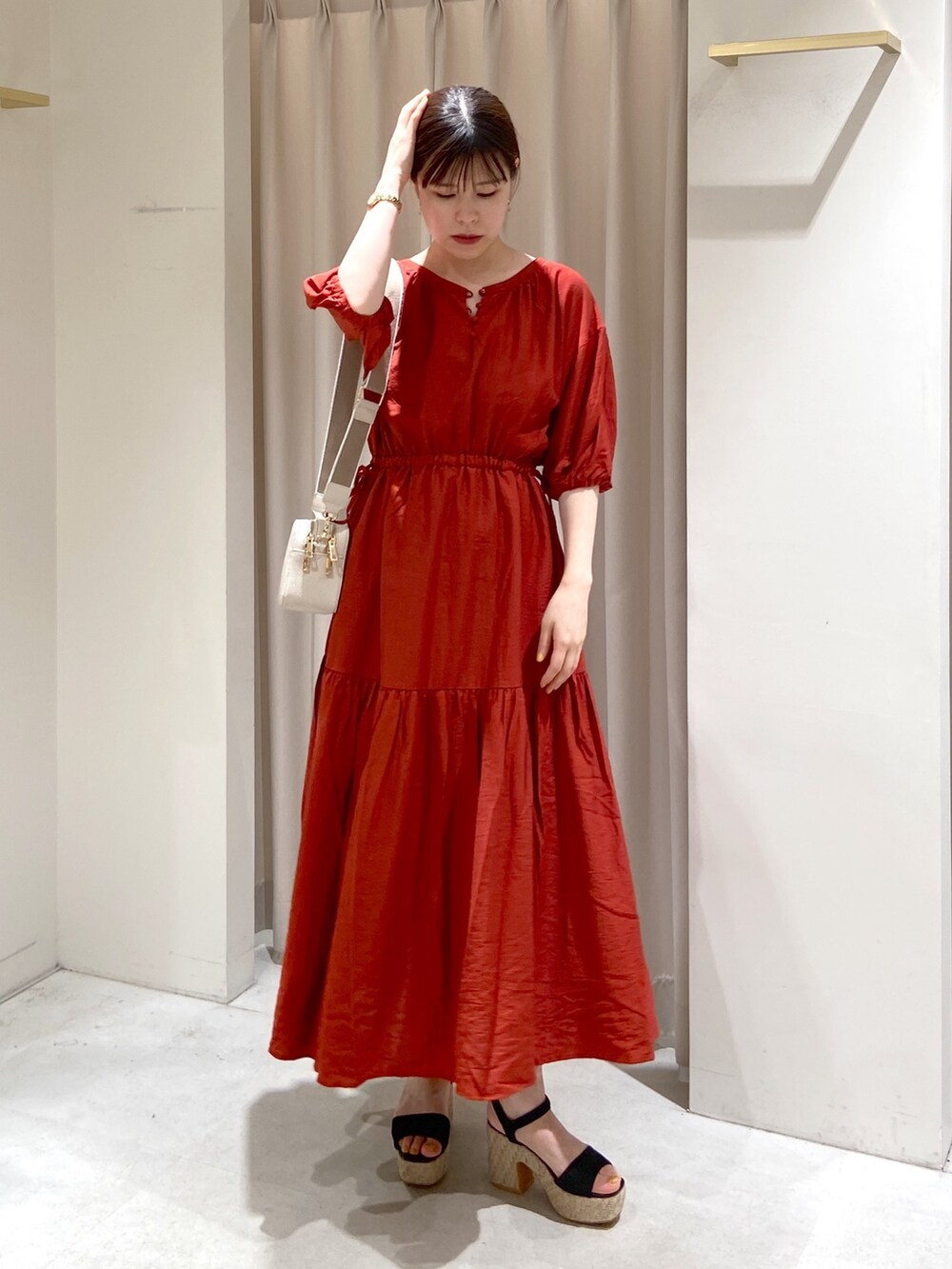 レッド系のワンピース、ホワイト系のボディバッグ/ウエストポーチ、ブラック系のサンダルを着用したレディースの春コーディネートの6枚目の写真