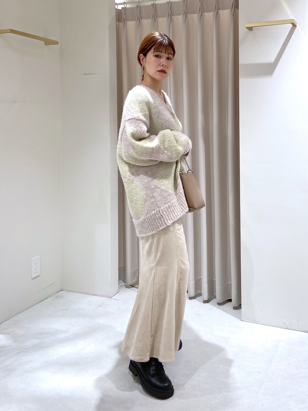 ベージュ系のショルダーバッグ、ブラック系のブーツ、ホワイト系のスカートを着用したレディースの秋コーディネートの3枚目の写真