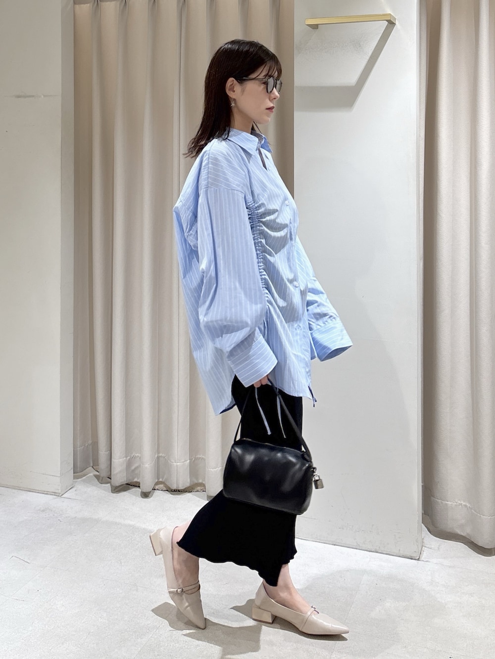 ブルー系のシャツ/ブラウス、ブラック系のハンドバッグ、ブラック系のスカートを着用したレディースの春コーディネートの3枚目の写真