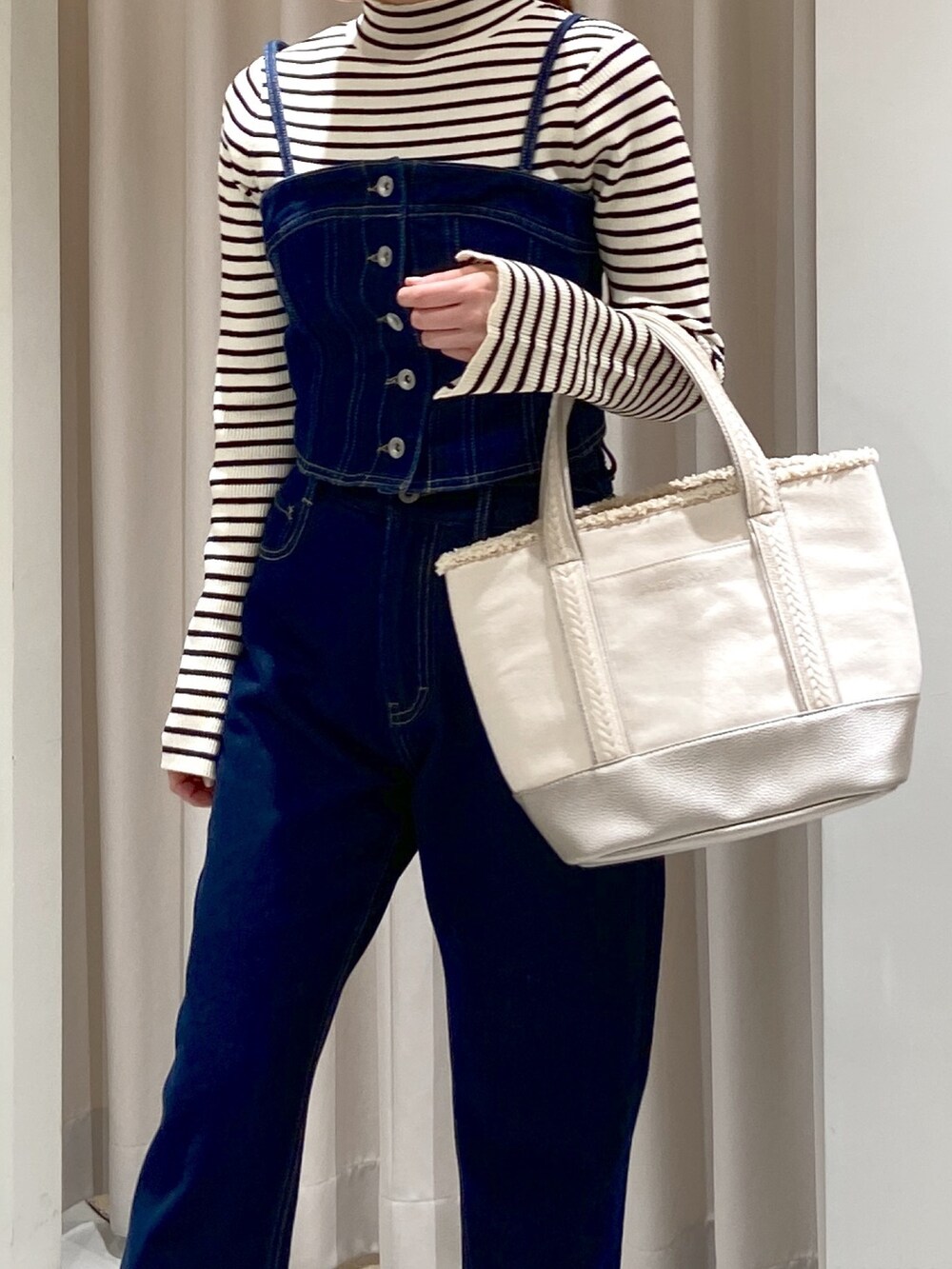 ホワイト系のニット/セーター、ブルー系のベスト、ブルー系のデニムパンツを着用したレディースの冬コーディネートの3枚目の写真