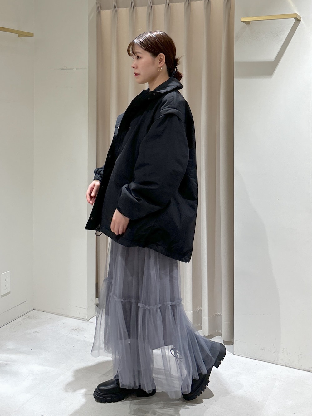 ブラック系のダウンジャケット/コート、グレー系のスカート、ブラック系のブーツを着用したレディースの秋コーディネートの4枚目の写真