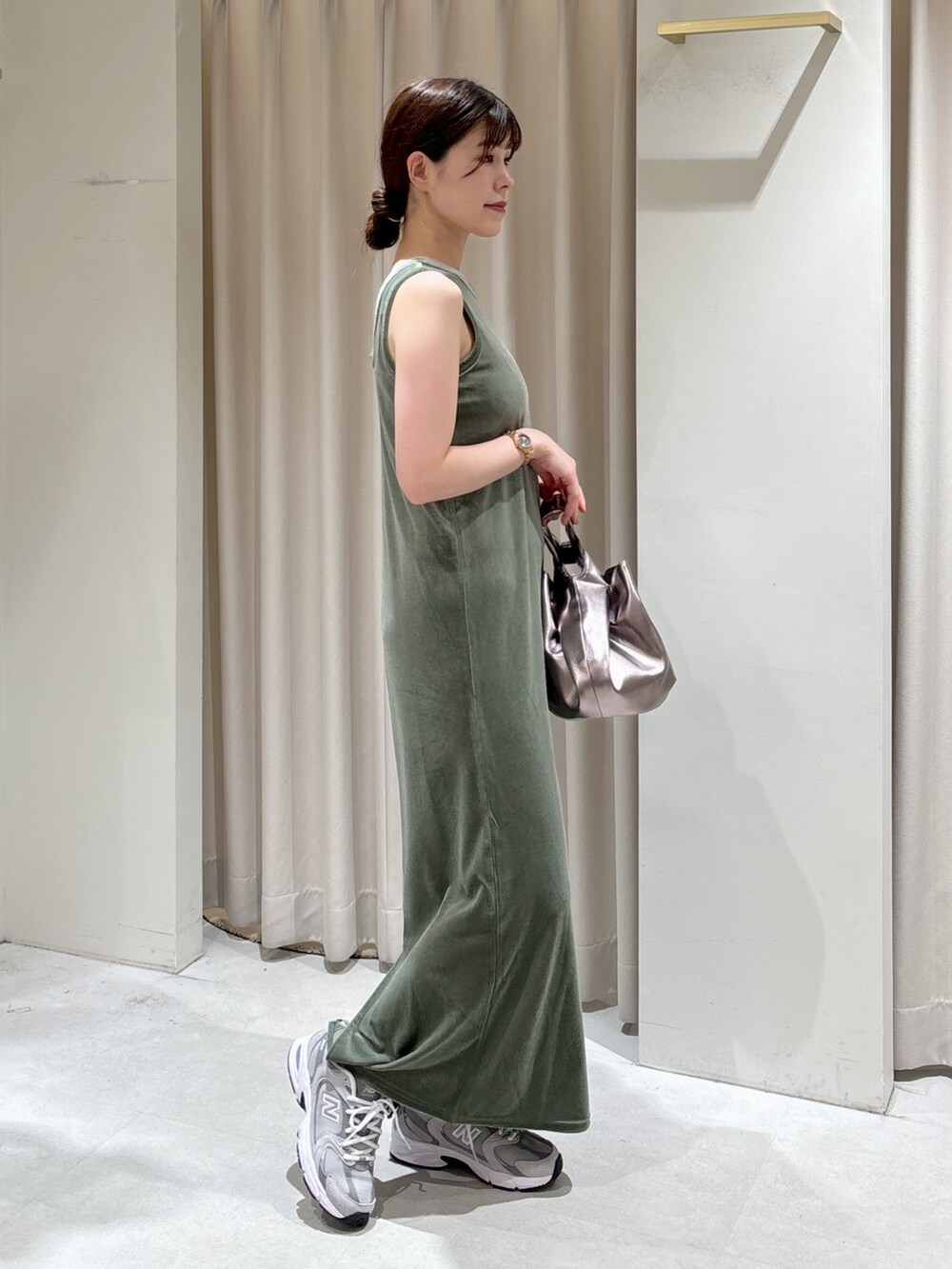 グリーン系のワンピース、シルバー系のハンドバッグ、グレー系のスニーカーを着用したレディースの秋コーディネートの2枚目の写真