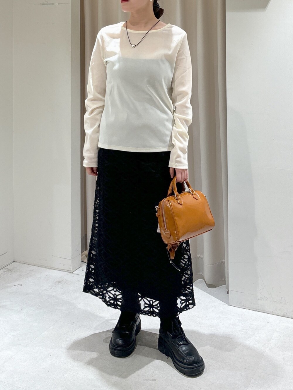 ブラック系のスカート、ベージュ系のショルダーバッグ、ブラック系のブーツを着用したレディースの冬コーディネートの6枚目の写真