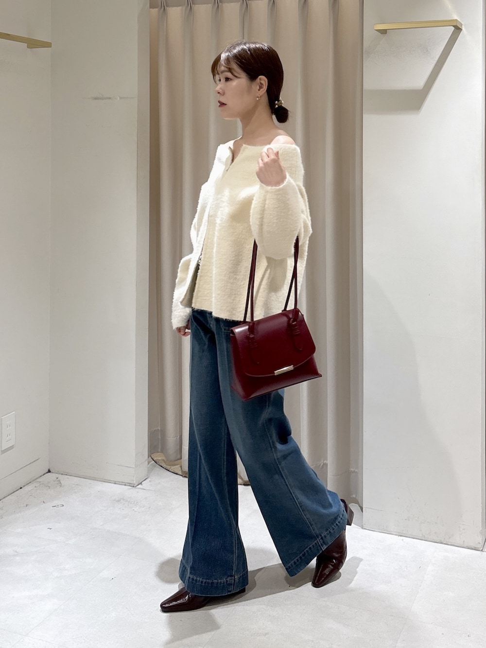 ホワイト系のニット/セーター、レッド系のトートバッグ、ブルー系のデニムパンツを着用したレディースの秋コーディネートの5枚目の写真