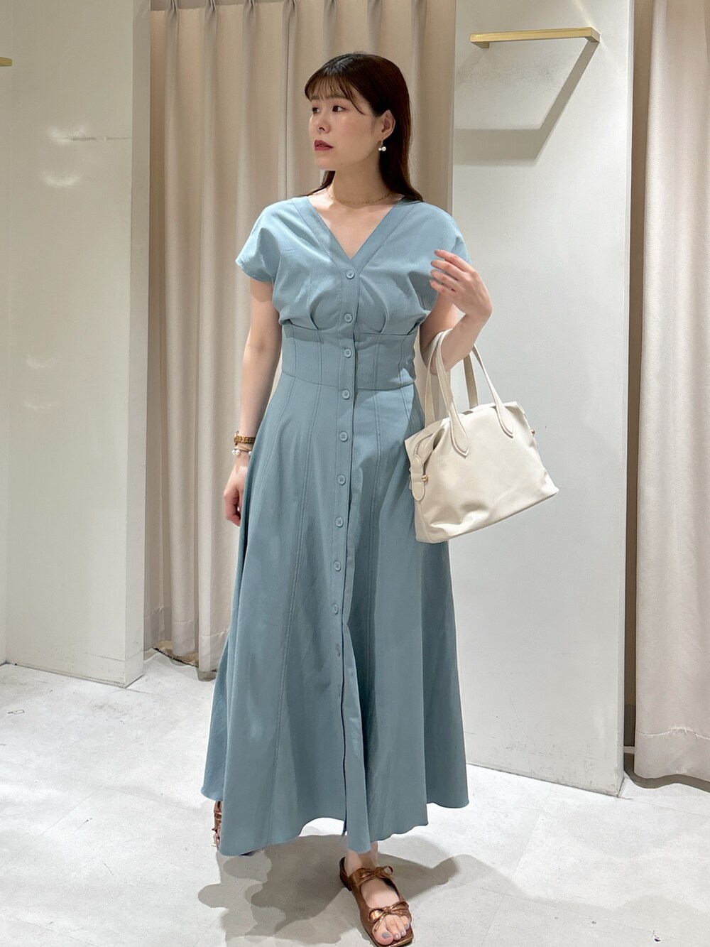 ブルー系のワンピース、ホワイト系のボストンバッグ、ブラウン系のサンダルを着用したレディースの夏コーディネートの6枚目の写真