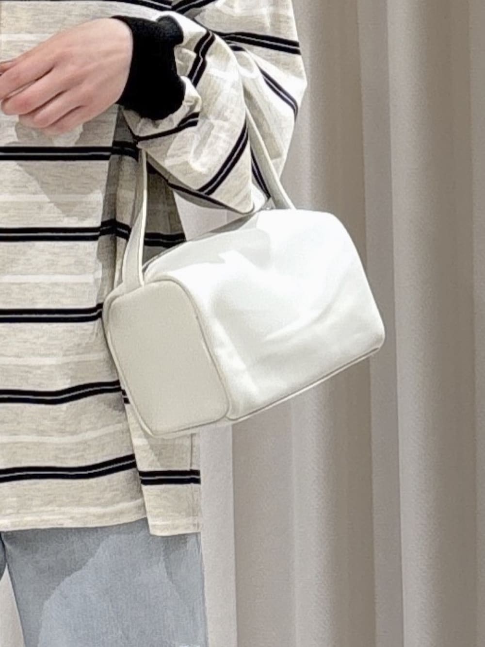 グレー系のTシャツ/カットソー、ホワイト系のハンドバッグ、ブルー系のデニムパンツを着用したレディースの春コーディネートの7枚目の写真