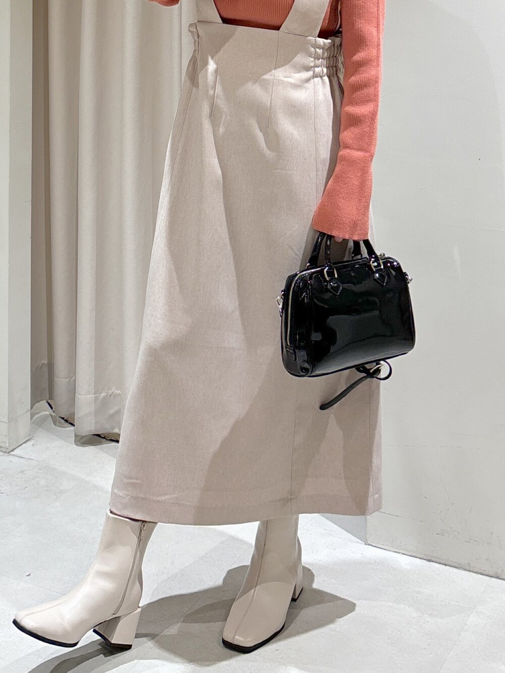 ピンク系のニット/セーター、ベージュ系のジャンパースカート、ブラック系のショルダーバッグを着用したレディースの冬コーディネートの4枚目の写真