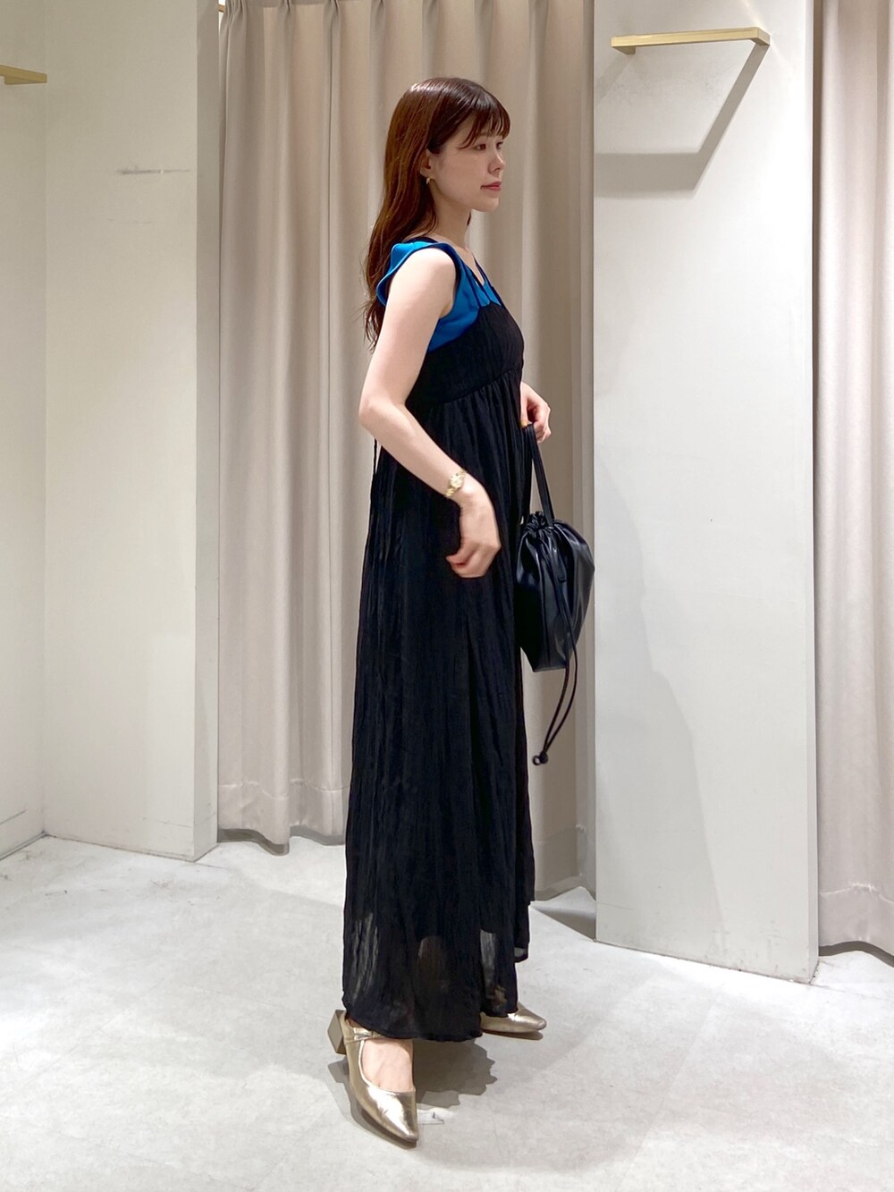 ブルー系のタンクトップ、ブラック系のハンドバッグ、ゴールド系のパンプスを着用したレディースの春コーディネートの2枚目の写真