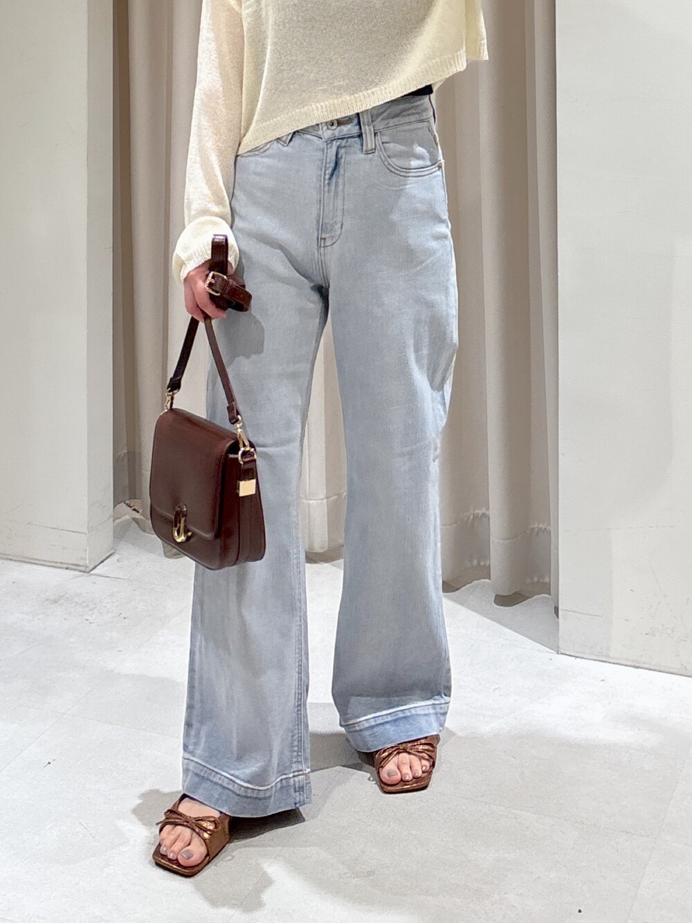 ブラウン系のハンドバッグ、ホワイト系のニット/セーター、ブラック系のキャミソールを着用したレディースの秋コーディネートの4枚目の写真