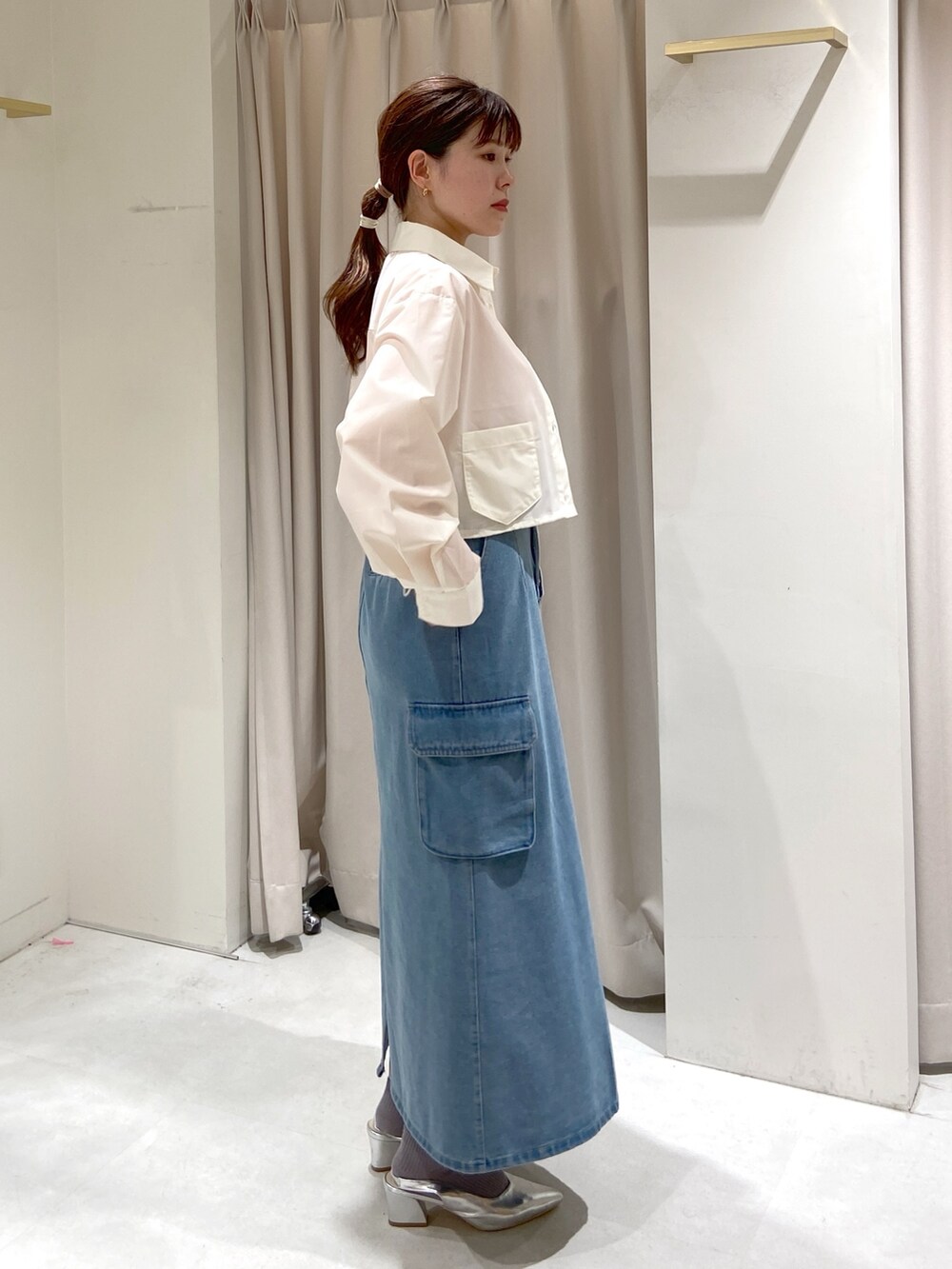 ブルー系のデニムスカート、ホワイト系のシャツ/ブラウス、オレンジ系のニット/セーターを着用したレディースの春コーディネートの4枚目の写真