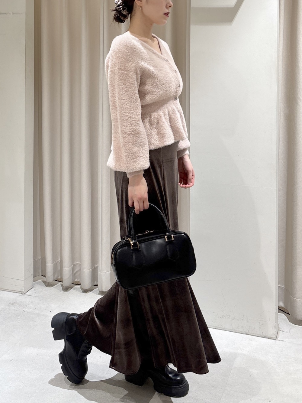 ピンク系のニット/セーター、ブラウン系のスカート、ブラック系のブーツを着用したレディースの冬コーディネートの3枚目の写真