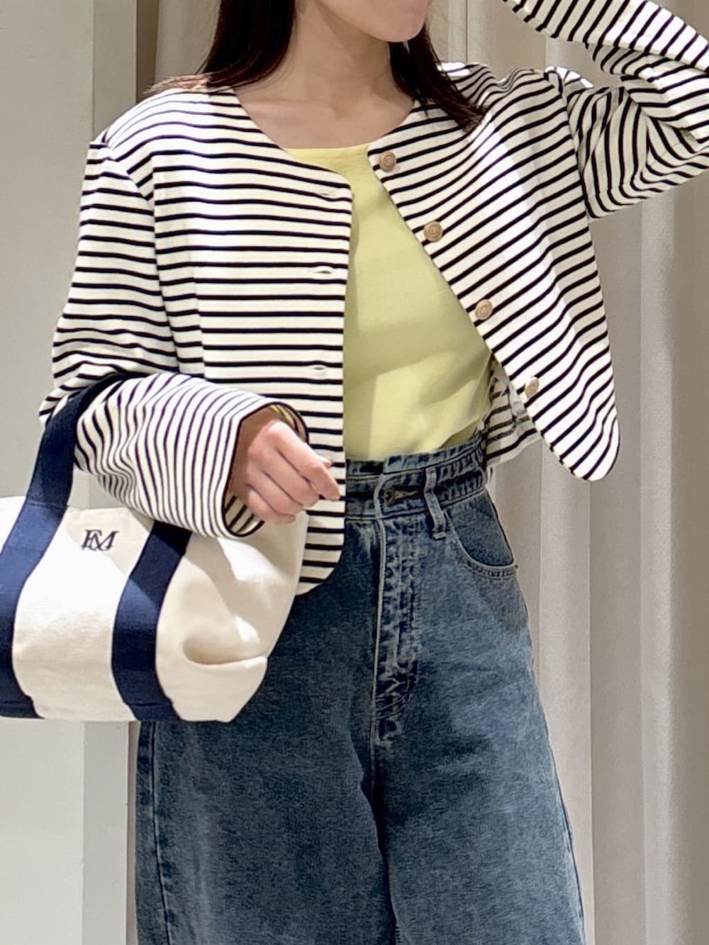 ブラック系のノーカラージャケット、イエロー系のニット/セーター、ブルー系のデニムパンツを着用したレディースの冬コーディネートの2枚目の写真