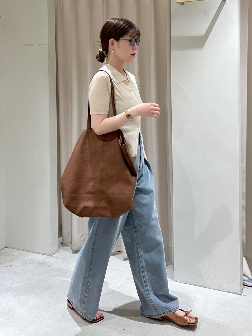 ブルー系のデニムパンツ、ブラウン系のサンダル、ブラック系のキャミソールを着用したレディースの春コーディネートの2枚目の写真